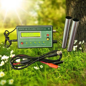 Pode incluir: Um gerador de frequência Rife & Clark Digital com uma caixa de controle retangular verde, uma tela LCD amarela exibindo "Wave: Sine Freq: 000528.00Hz", cinco botões circulares, um interruptor vermelho, dois cilindros metálicos e cabos pretos.
