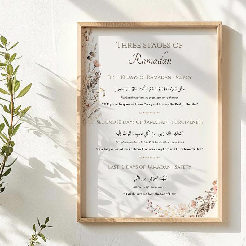 May include: A framed print with the text "Three Stages of Ramadan" in elegant script. The print includes Arabic text and English translations, with floral accents in the corners. The frame is a light wood color.