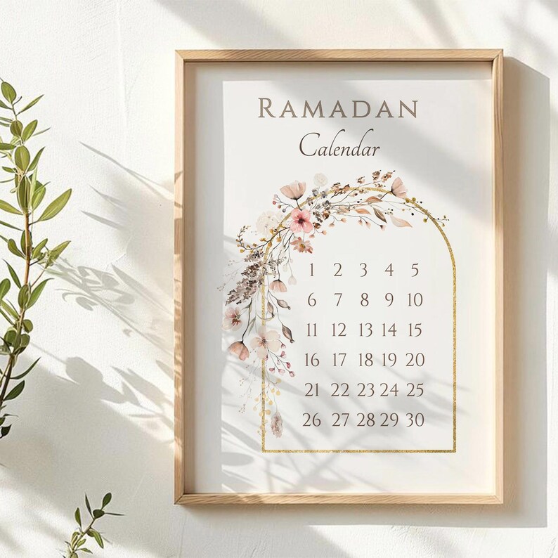 May include: A framed Ramadan calendar with a floral design. The calendar features the word "RAMADAN" above the word "Calendar". The calendar dates are displayed within a gold arch, and the frame is made of light wood.