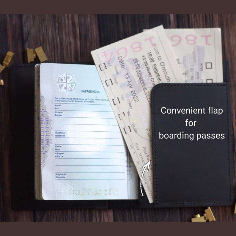 K&ouml;nnte beinhalten: Schwarzer Leder-Reisepasshalter mit praktischer Klappe f&uuml;r Bordkarten. Der Reisepasshalter ist ge&ouml;ffnet und zeigt einen Reisepass und Tickets. Der Text "Convenient flap for boarding passes" ist auf der Klappe zu sehen.