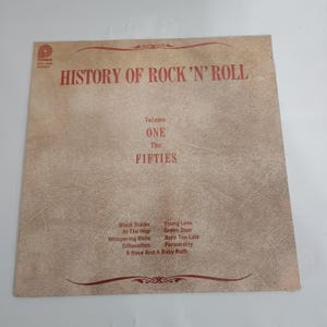 May include: Vintage vinyl record album cover titled "History of Rock 'N' Roll, Volume One, The Fifties." The cover is tan with red text and a list of songs including "Black Slacks" and "Young Love."