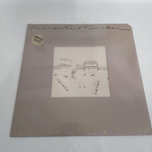 Pode incluir: Um álbum de vinil de Ferrante & Teicher, com um esboço de duas figuras com teclados. A capa do álbum é de cor castanho claro com o texto "Special Value" e "The ABC Collection".