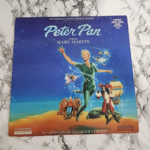 May include: A vintage Peter Pan Laserdisc cover featuring Mary Martin. The cover art depicts Peter Pan, Captain Hook, and other characters from the musical against a blue starry background. Text includes "The Original Family Musical Classic" and "30th Anniversary Collector's Edition."