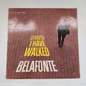 Può includere: Copertina di un album in vinile vintage per "Streets I Have Walked" di Belafonte. La copertina presenta uno sfondo a motivo di mattoni con la silhouette di una persona che cammina. Il titolo dell'album è in testo giallo e bianco.
