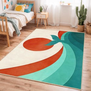 Puede incluir: Una alfombra rectangular con un diseño retro. La alfombra presenta un gran círculo naranja, una franja roja curva y un patrón de olas turquesas sobre un fondo crema. El diseño evoca un tema de puesta de sol u océano.