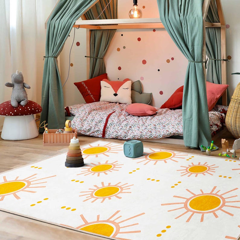 May include: A child's bedroom scene featuring a white rug with yellow sun designs. The room includes a wooden bed frame with green curtains, red pillows, and a floral patterned duvet. A mushroom-shaped stool and a wooden toy are also visible.
