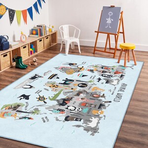 Könnte beinhalten: Ein hellblauer rechteckiger Teppich mit einer illustrierten Weltkarte mit verschiedenen Tieren. Der Teppich trägt den schwarzen Schriftzug "ANIMAL WORLD". Der Teppich befindet sich in einem Kinderspielzimmer mit einem weißen Stuhl, einer Staffelei und Holzregalen.