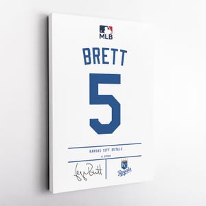 May include: White canvas art print featuring the MLB logo and the name "BRETT" above the number "5" in blue. Below, it reads "KANSAS CITY ROYALS" and includes a signature and team logo.