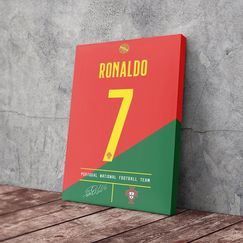 K&ouml;nnte beinhalten: Leinwanddruck mit einem rot-gr&uuml;nen Design, das den Namen "RONALDO" in Gelb zeigt. Die Zahl "7" ist gelb. Der Text "PORTUGAL NATIONAL FOOTBALL TEAM" befindet sich unten, zusammen mit einer Unterschrift und einem Wappen.