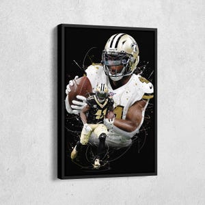 May include: Framed artwork featuring a football player in a white and gold uniform, holding a football. A smaller image of another player in a black and gold uniform is superimposed. The background is black with white and gold paint splatter effects.