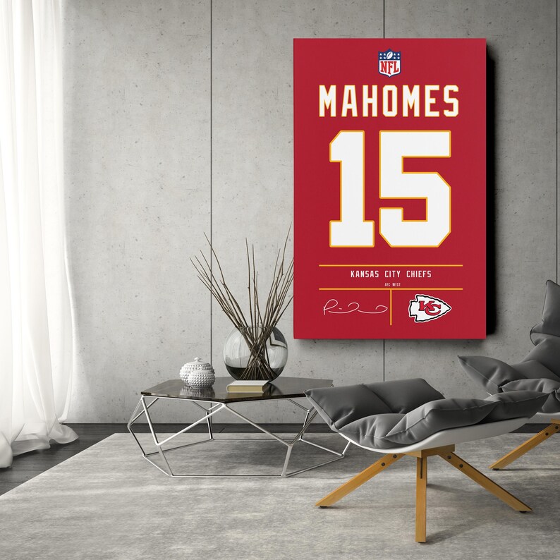 May include: A red canvas print of a Kansas City Chiefs jersey, featuring the name "MAHOMES" and the number "15" in white. The NFL logo and team logo are visible. The print is displayed on a gray wall.