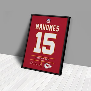 May include: Framed red Kansas City Chiefs jersey art featuring "MAHOMES" and the number "15" in white. The NFL logo is at the top, with "KANSAS CITY CHIEFS" and a signature at the bottom. The frame is black.