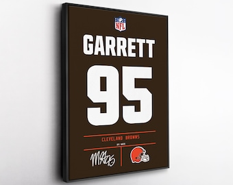 May include: Framed artwork featuring a Cleveland Browns jersey design. The jersey displays "GARRETT" and the number "95" in white on a brown background. Includes the NFL logo, team name, and a signature.