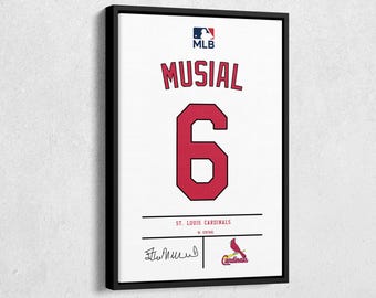 以下が含まれることがあります： 「MUSIAL」のネームと赤い「6」の数字が入った白いユニフォームの額装アート。MLBのロゴが上部にあり、「St. Louis Cardinals」とサインが下にあります。赤いカーディナルのロゴも表示されています。
