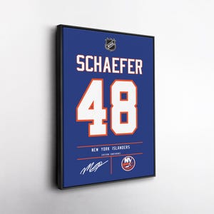 May include: Framed New York Islanders hockey jersey with the name "SCHAEFER" and the number "48" in white on a blue background. Includes the NHL logo and team details. The jersey is framed in a black border.