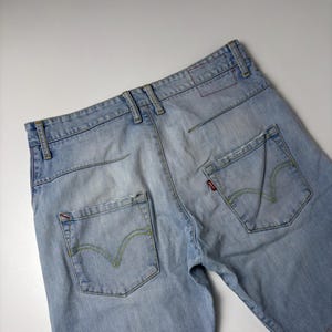 Op de afbeelding: Lichtblauwe denim shorts met een klassieke vijf-zakken stijl. Voorzien van een rood Levi's label op de achterzak, gele stiksels en distressed details. De shorts zijn gemaakt van licht gewassen denim.