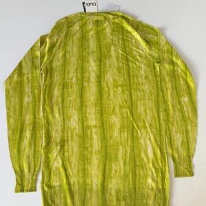 May include: A long-sleeved, lime green sweater with a vertical striped pattern. The sweater has a ribbed hem and cuffs, and a small tag is attached near the neckline. The fabric has a subtle sheen.
