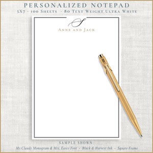 May include: A personalized notepad with the text "ANNE AND JACK" in gold lettering. The notepad is 5x7 inches and has 100 sheets of ultra-white paper. A gold pen rests on the notepad. The notepad is framed with a thin black border.