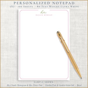 May include: A personalized notepad with a pink border and the text "hm HALLIE MORGAN" in a script font. A gold pen rests on the notepad. The notepad is 5x7 inches and has 100 sheets.