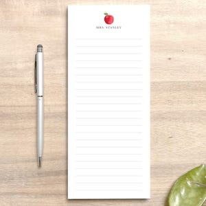 May include: White notepad with lined paper and a red apple illustration at the top. The text "Mrs. Stanley" is printed below the apple.