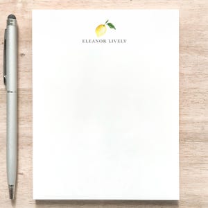 May include: A white notepad with a lemon illustration and the text "Eleanor Lively" at the top.