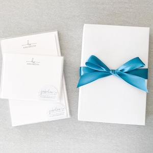 May include: A set of white stationery cards with a handwritten monogram and the name "Kara Sweeten" printed on each card. The cards are packaged in a white box with a teal ribbon.