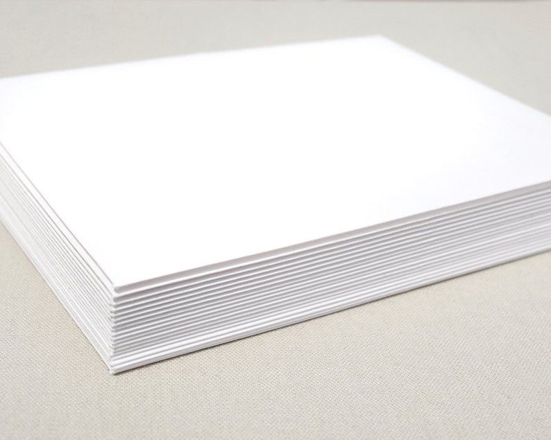 May include: A stack of white cardstock paper. The paper is smooth and has a slight sheen.