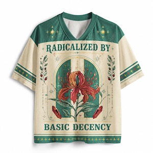 Puede incluir: Una camiseta de cuello en V color crema y verde con un gráfico central de un lirio rojo y naranja, dos cristales rojos y ramas con hojas. El texto RADICALIZED BY BASIC DECENCY está impreso en letras verde oscuro sobre y bajo la ilustración.