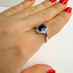 Sterling silver sapphire ring shown from below, open basket setting visible beneath the oval stone with band detail in focus