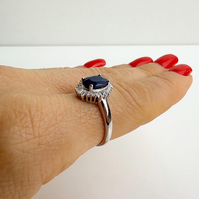 Sapphire halo ring resting on a palm, full ballerina halo visible from directly above with baguette stones fanning outward