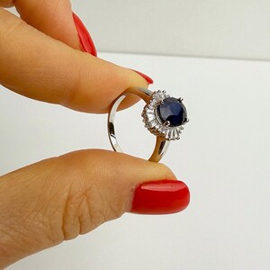 Reverse side of a silver ring showing the hallmark stamp and open metalwork beneath the sapphire setting