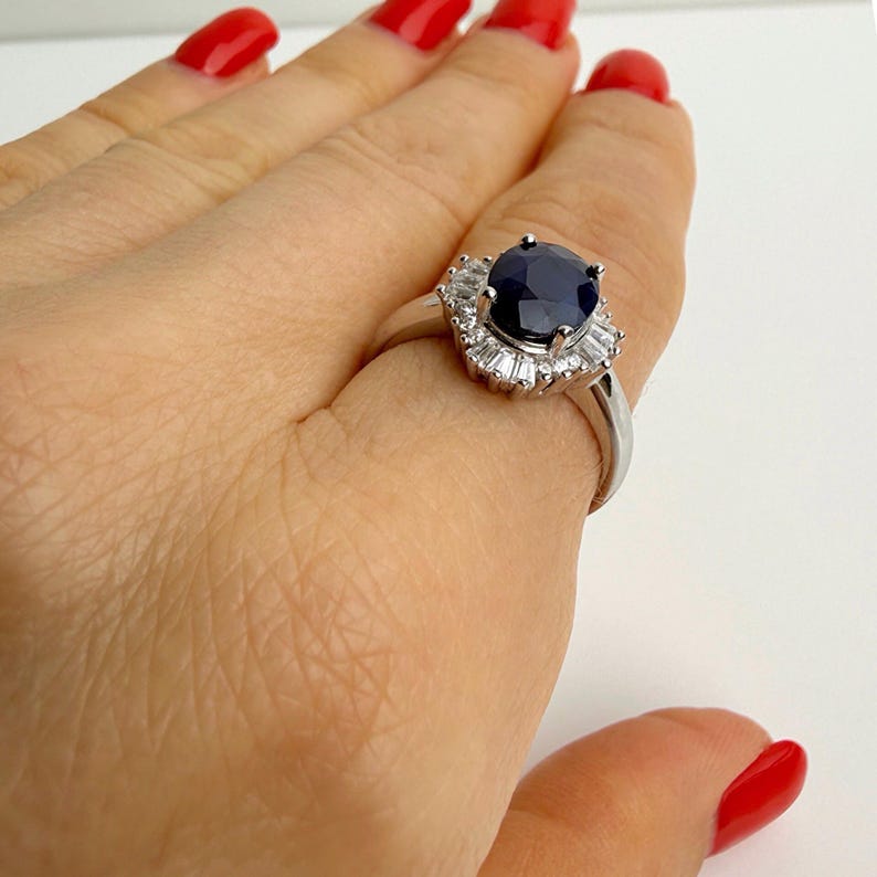 Blue sapphire ring worn on the index finger, side view showing stone height and band width in natural proportion