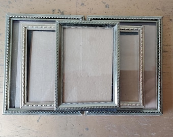 May include: Three silver picture frames with ornate borders, nested inside each other. The frames are empty and ready for photos.