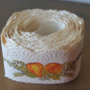Puede incluir: Un rollo de encaje de papel blanco con un borde festoneado y un dise&ntilde;o impreso de peras naranjas y hojas verdes.