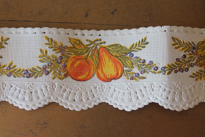 Puede incluir: Borde de encaje blanco con un borde festoneado y un dise&ntilde;o impreso de hojas amarillas y verdes, fruta naranja y peras amarillas.