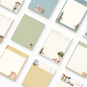 May include: A collection of decorative notepads with various designs. Each notepad features a different color and illustration, including a squirrel, bunny, and house. Some notepads have text such as "To-Do" and "Notes".