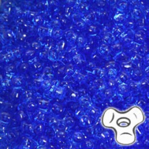 May include: A close-up view of a large quantity of small, translucent blue glass beads. The beads are irregularly shaped and have a slightly cloudy appearance.