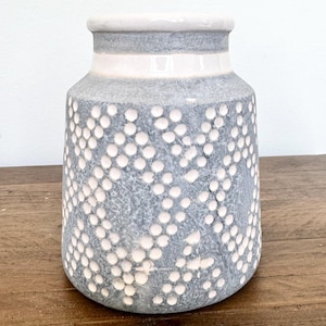 May include: A set of three ceramic mugs with a speckled, matte finish. The mugs are in shades of cream, light gray, and dark gray. Each mug has a simple, minimalist design, perfect for coffee or tea.