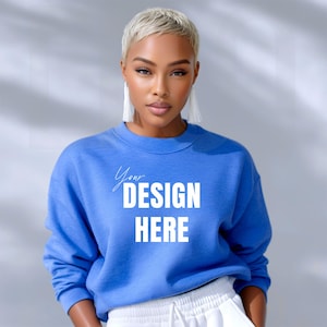 May include: A blue sweatshirt with the text "Your DESIGN HERE" in white. The sweatshirt is worn by a person with short blonde hair and white tassel earrings. The person is also wearing white pants.