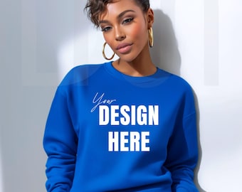 May include: A royal blue sweatshirt with the text "Your DESIGN HERE" in white. The sweatshirt is a crew neck style. The model is wearing gold hoop earrings and black leather pants.