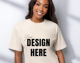 May include: A cream-colored t-shirt with the text "Your DESIGN HERE" in black. The shirt has short sleeves and a relaxed fit. The model is smiling and has long, dark hair.