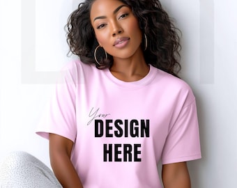 May include: A light pink t-shirt with the text "Your DESIGN HERE" in black. The shirt has short sleeves and a crew neck. The model is wearing gold hoop earrings.