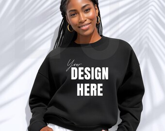 May include: Black sweatshirt with the text "Your DESIGN HERE" in white. The sweatshirt is a crew neck style. The model is wearing white pants and gold hoop earrings.