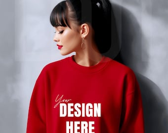 May include: A red sweatshirt with the text "Your DESIGN HERE" in white. The sweatshirt is being worn by a person with dark hair pulled back in a ponytail. The person is wearing gold earrings and red lipstick.