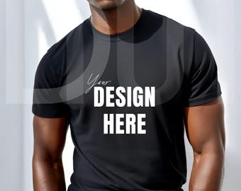 Puede incluir: Camiseta negra de cuello redondo con el texto "Your DESIGN HERE" en blanco. La camiseta de manga corta está hecha de un material negro liso. El diseño está centrado en la parte delantera de la camiseta.