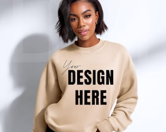 May include: A beige sweatshirt with the text "Your DESIGN HERE" in a script font and bold, black capital letters. The sweatshirt has a crew neck and long sleeves. The model is wearing black shorts.