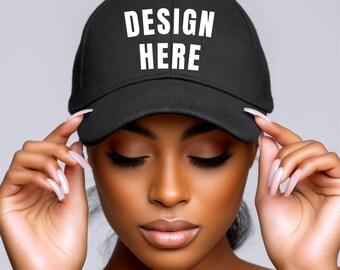 May include: Black baseball cap with the text "DESIGN HERE" in white block letters. The cap has a curved brim and a structured fit. The cap is being held by a person.