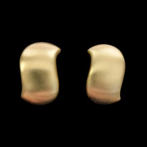 May include: A pair of gold-toned earrings featuring a smooth, curved, S-shaped silhouette. The metal surface has a soft, matte finish that reflects light gently along the rounded edges of each piece, creating a consistent and uniform appearance.