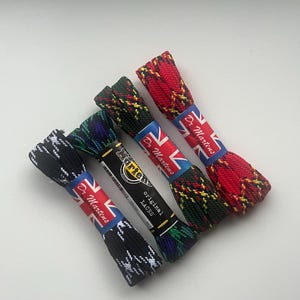 Peut inclure: Plusieurs lacets originaux Dr. Martens, avec différents motifs écossais. Les lacets sont noirs et blancs, verts et bleus, et rouges et jaunes. Chaque paire est emballée avec une étiquette avec le drapeau britannique et le logo Dr. Martens.