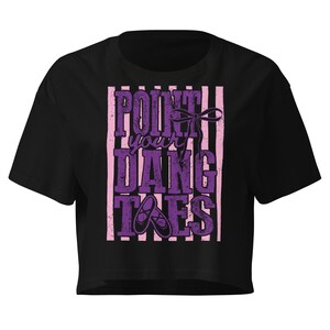 May include: Black crop top with a purple and pink graphic. The graphic reads "Point Your Dang Toes" with a bow and ballet shoes. The shirt has short sleeves and a crew neck.